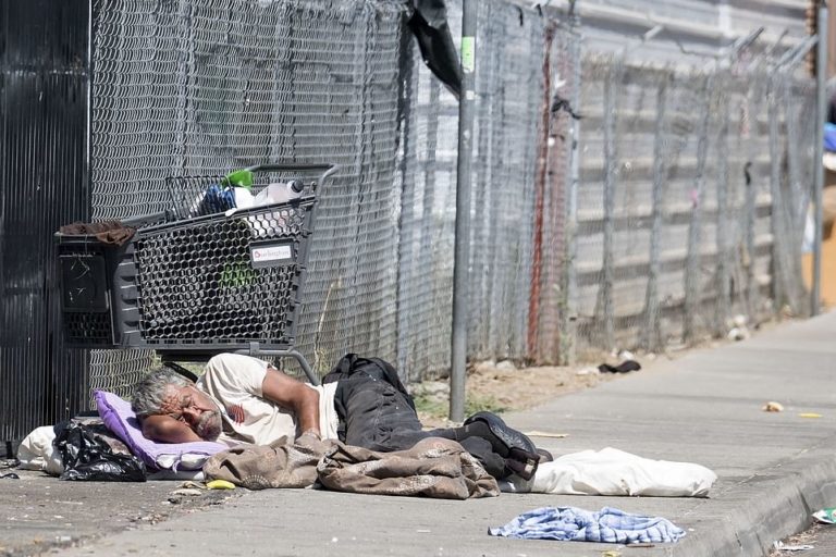 Protect CA - News - Image of a man sleeping on the sidewalk in broad daylight in Sacramento